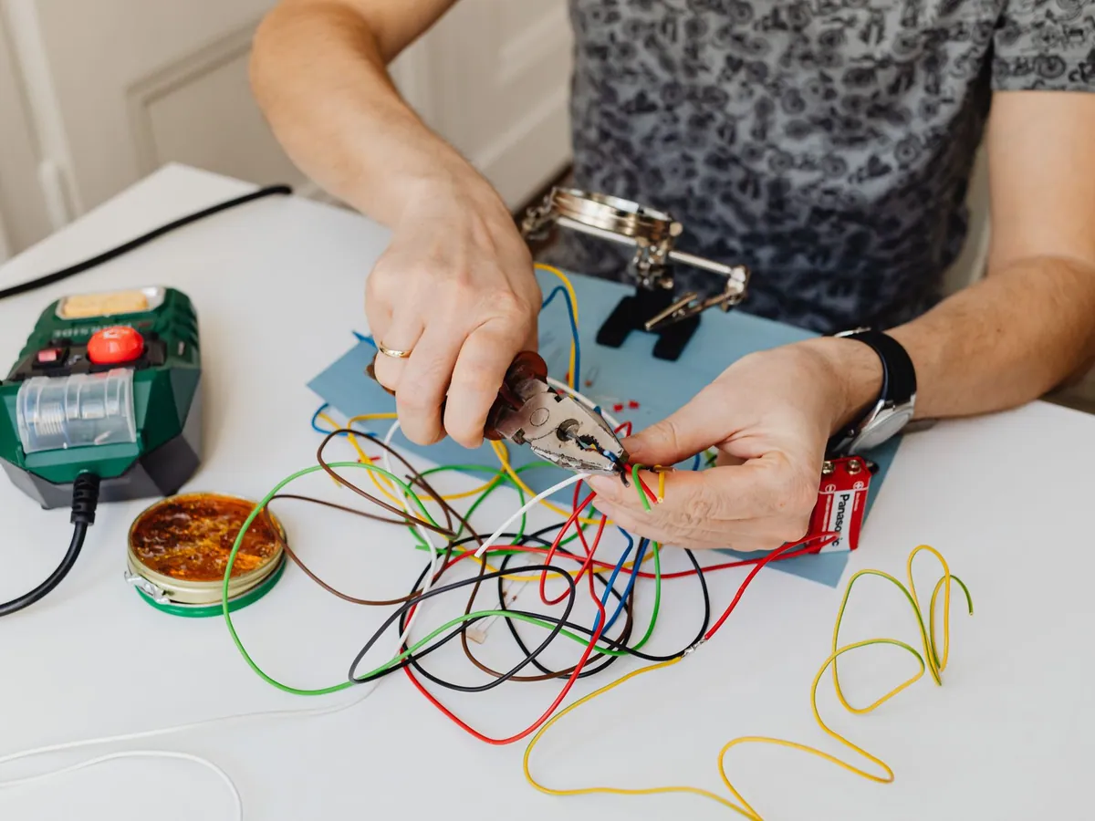 A technician precisely cuts and organizes colorful wires using pliers, showcasing expertise in wiring tasks.